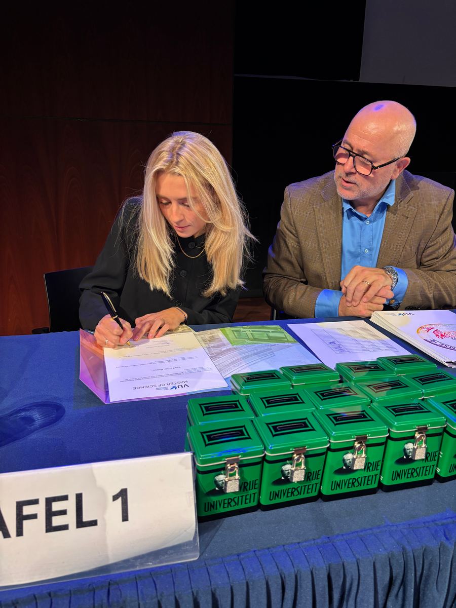 Eva tekent bij de uitreiking van haar master aan de Vrije Universiteit